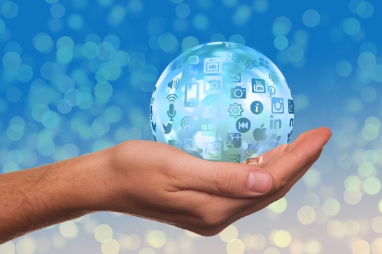 image shpowing a hand holding a blue ball covered with social media icons 